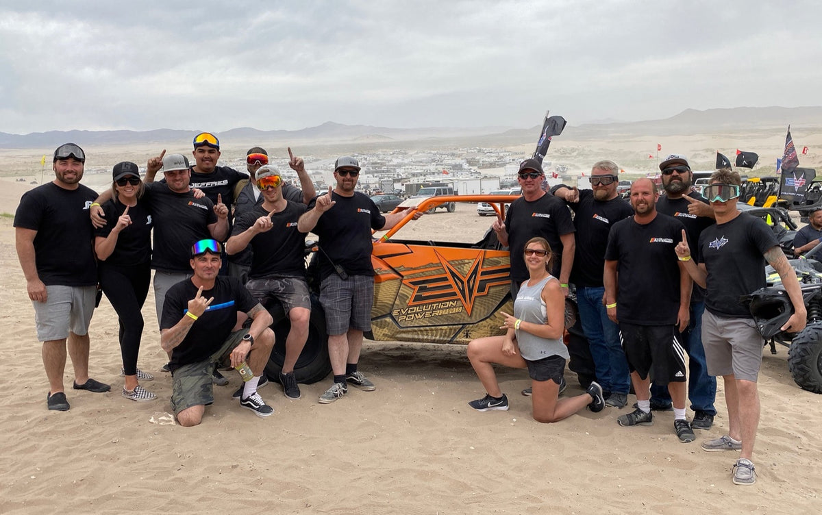EVP team and riders gathered with a UTV at a dune event